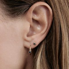 Close-up of a Birthstone Stud and Birthstone Hoop in Sapphire (September) in yellow gold in a brunette woman's ear.
