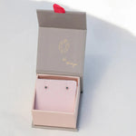 A pair of Birthstone Studs - Sapphire (September) in a Maya Brenner jewellery box against a light grey background. 