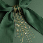 Gold necklaces with various pendants on a green fabric background