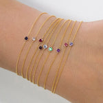 Gold bracelets with colorful gemstones on a wrist against a neutral background