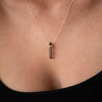 Close-up of a décolletage wearing The Courage Retreat Necklace with a black top. 