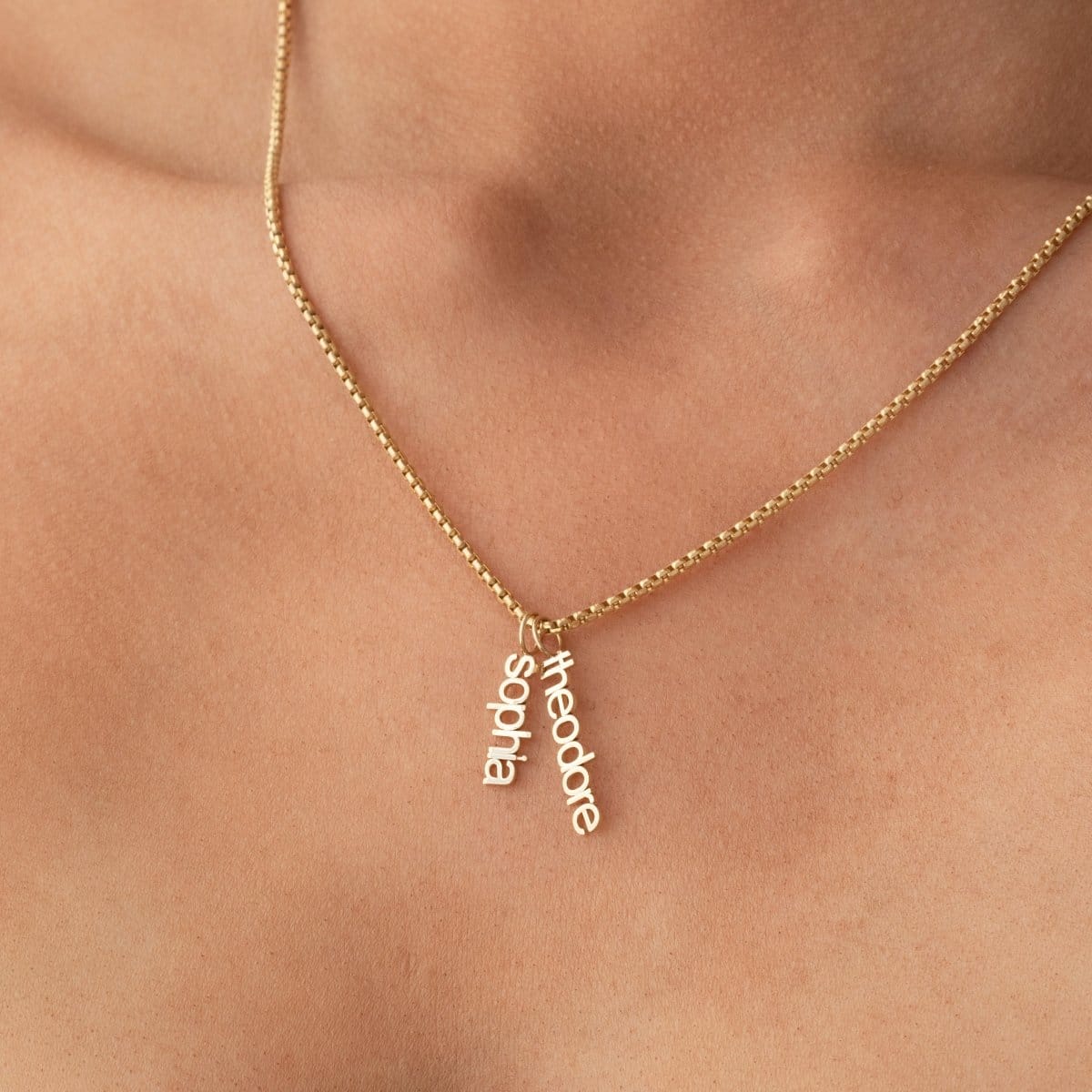 Gold necklace with name pendants on a person's neck