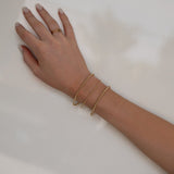 A hand wearing a Classic Bubble Bracelet Set, two Delicate Beaded Bands and a Twinkle Twinkle ring against a neutral background.