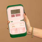 A Travel Jewelry Case - Green/Pink on a light brown background. 