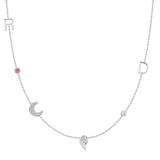 A Custom Gold Necklace in white gold with six charms, the letters R and D, two birthstones, a pavé moon and an angel wing, on a white background.
