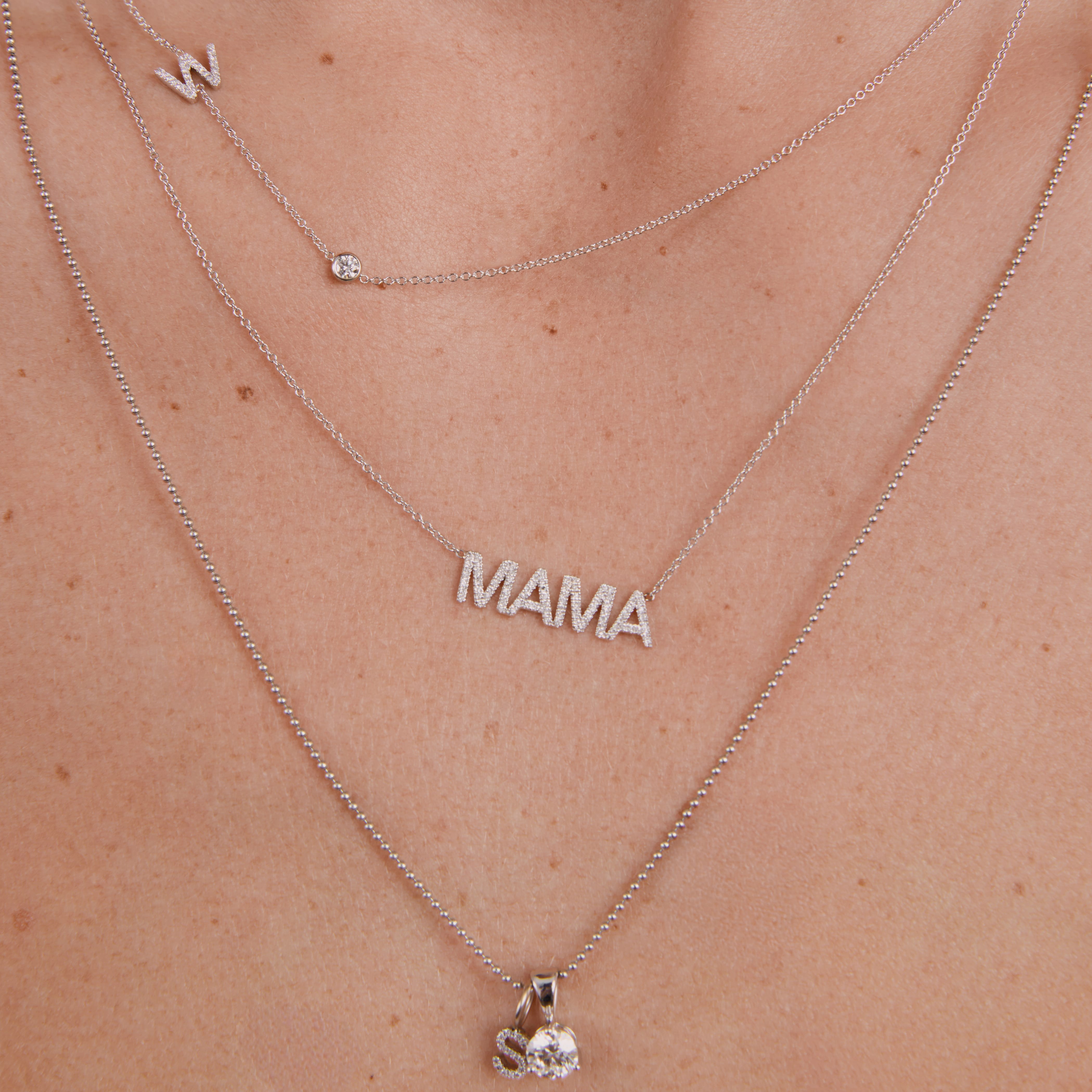 Silver 'MAMA' necklace on a person's neck with a close-up view.