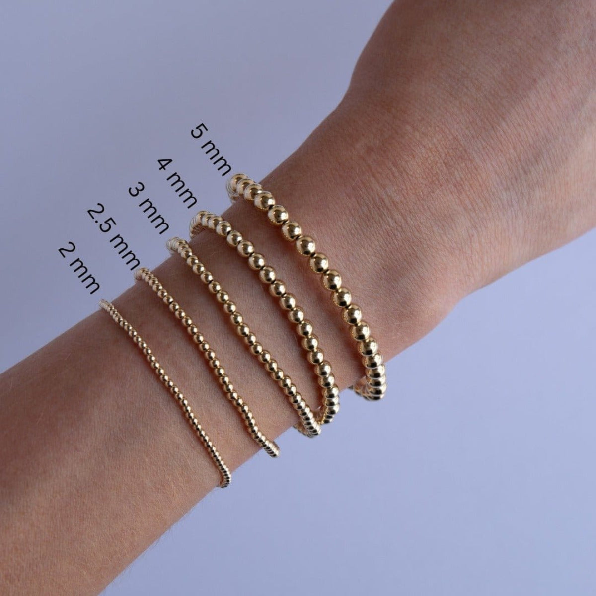 Yellow gold Bubble Bracelets of different sizes on a wrist with size measurements.