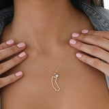 Close-up of a woman's decellotage wearing a California Necklace with a Duchess Diamond Pendant, held by her hands with light pink nails. 