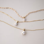 A Duchess Diamond Pendant on an Element Long Link Chain, a Princess Diamond Pendant on The Slide Chain and a Queen Diamond Pendant on a bead Chain in yellow gold against a light grey background. 