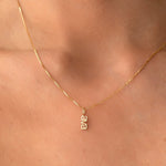 A close-up of a neck wearing a yellow gold Petite Nameplate Pendant with 'ava' on a necklace. 