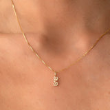 A close-up of a neck wearing a yellow gold Petite Nameplate Pendant with 'ava' on a necklace. 