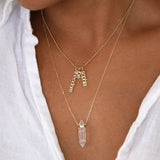 Close-up of a person's neck wearing a yellow gold Classic Bead Chain with three Petite Nameplate Pendants (sophia, joe and theodore) and The Clarity Retreat Necklace.