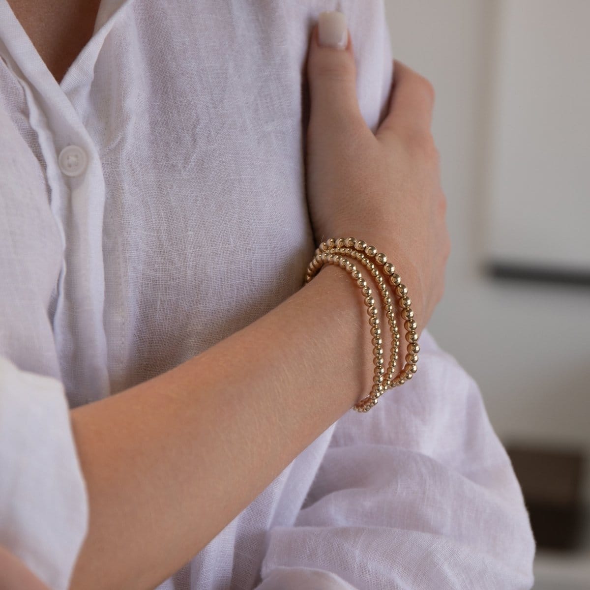 A woman's arm wearing the Statement Bubble Bracelet Set with a white linen shirt.