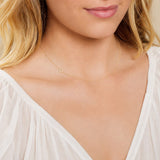 Close-up of a woman's neck wearing a rose gold necklace with a letter O charm.