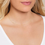 Close-up of a woman's neck wearing a yellow gold necklace with a letter J charm.