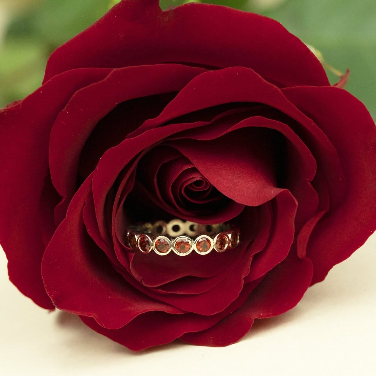 The Rose Bouquet Ring in a rose flower against a blurred green and cream background. 