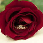 The Rose Bouquet Ring in a rose flower against a blurred green and cream background. 