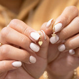 Charmed I'm Sure Hoops, one Star and the other Heart, being held by hands with light nails against a blurred background. 