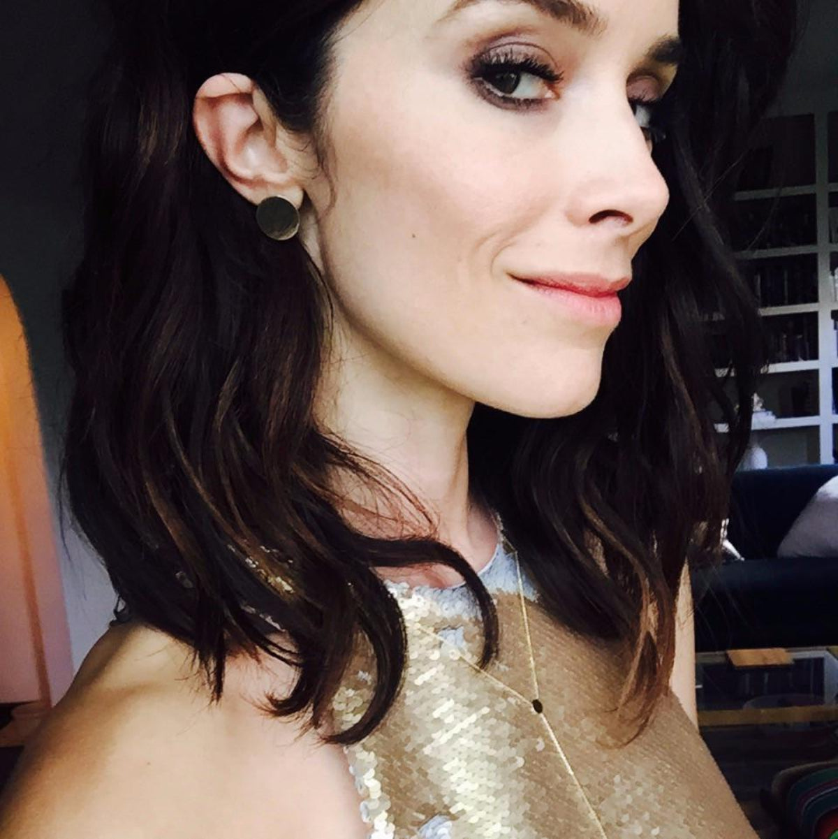 A woman wearing a yellow gold Solid Eclipse Earring - Large with brown hair and a gold top. 