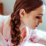 Woman wearing a gold 'B' letter stud earring. 