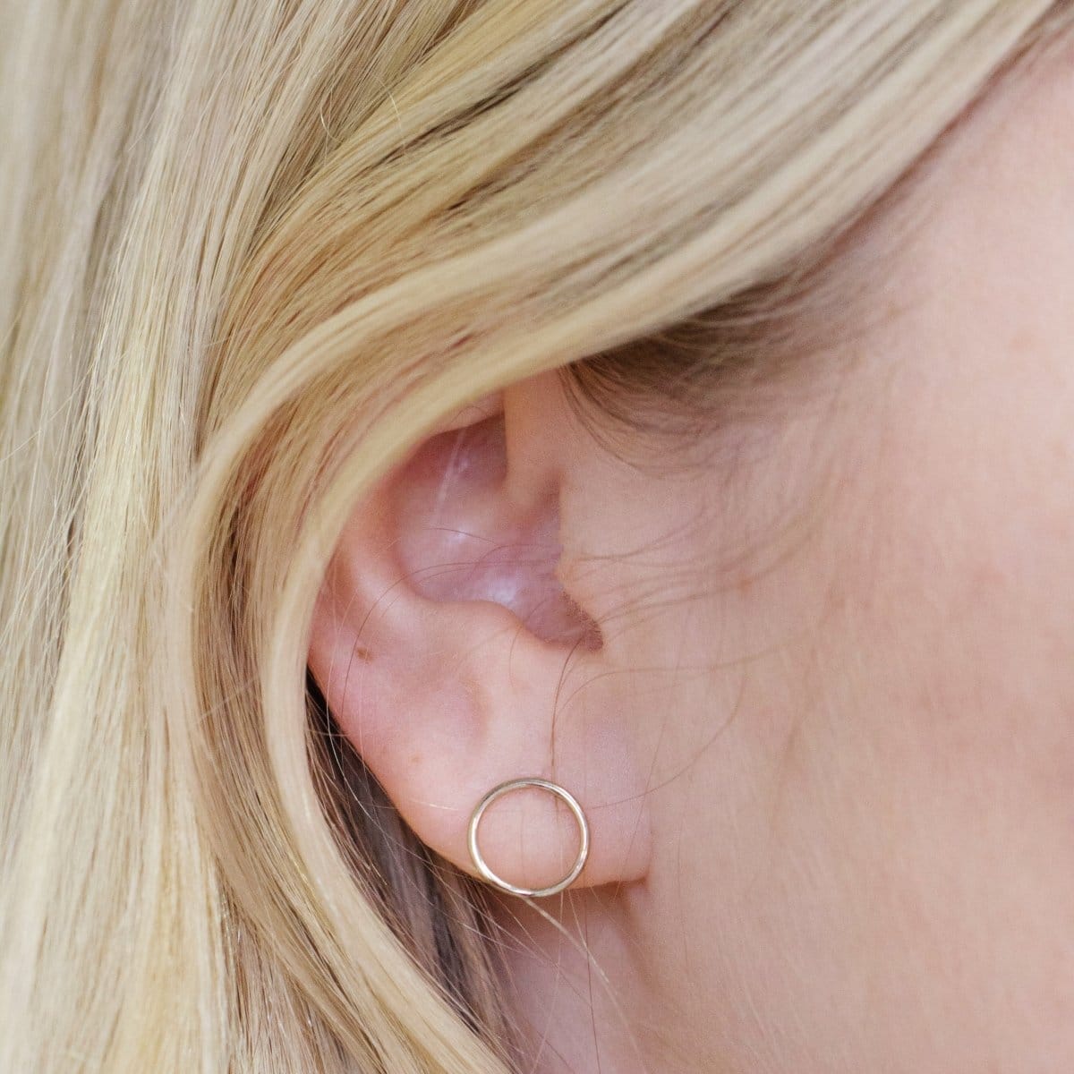 Close-up of a yellow gold Open Eclipse Earring - Small in a blonde woman's ear. 