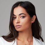 Woman wearing a gold pave single letter M stud. 