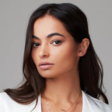 Woman wearing a gold pave single letter M stud. 