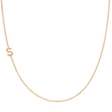 A rose gold necklace with a pave letter S charm on a white background. 