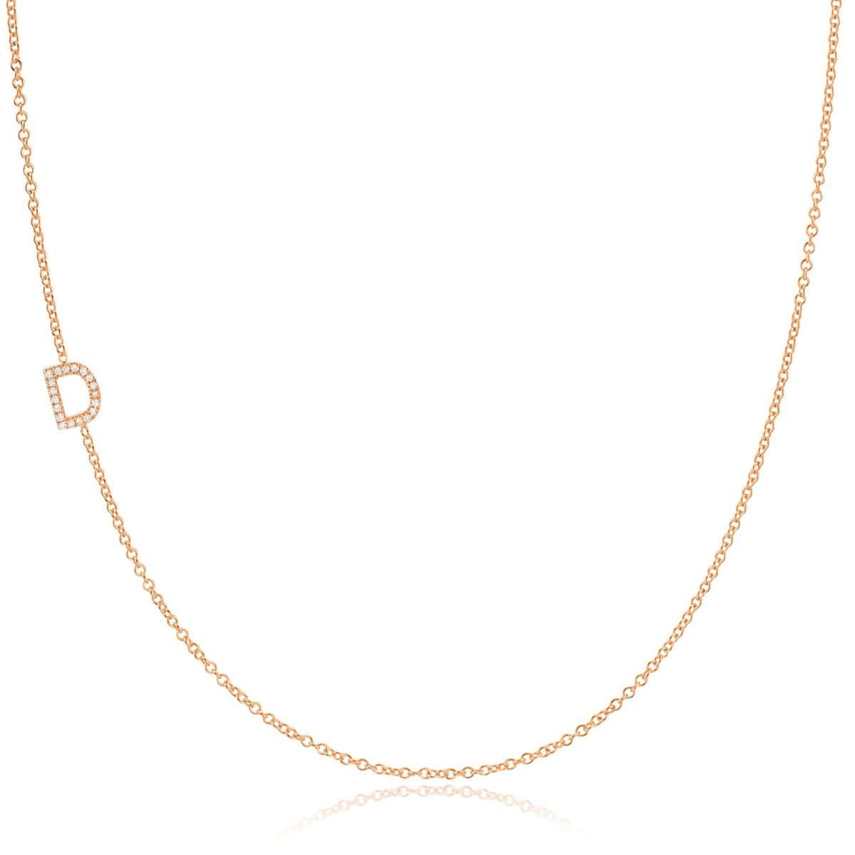 A rose gold necklace with a pave letter D charm on a white background. 