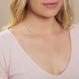 Close-up of a woman's neck wearing a rose gold necklace with a letter L charm. 