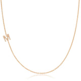 A rose gold necklace with a pave letter M charm on a white background. 