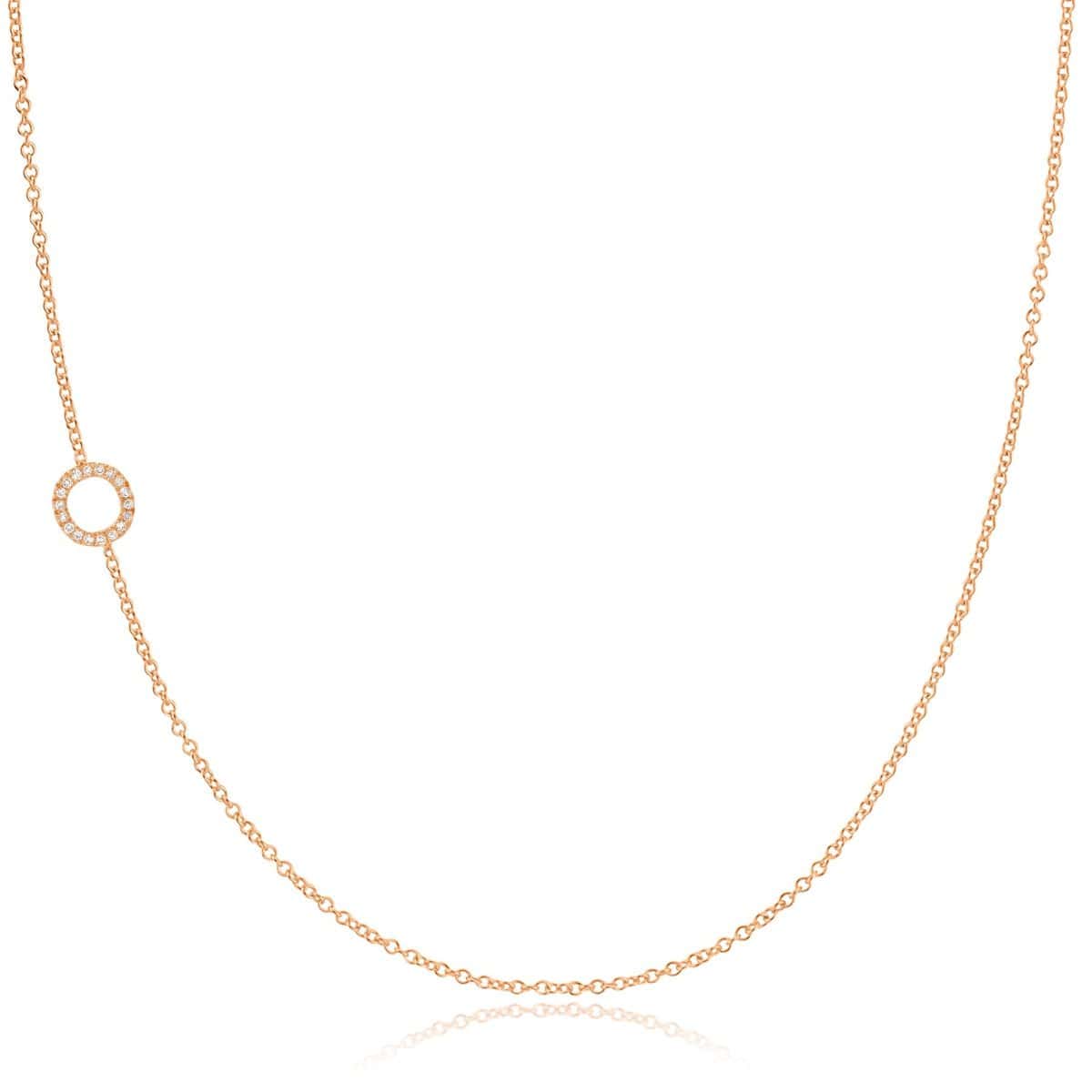 A rose gold necklace with a pave letter O charm on a white background. 