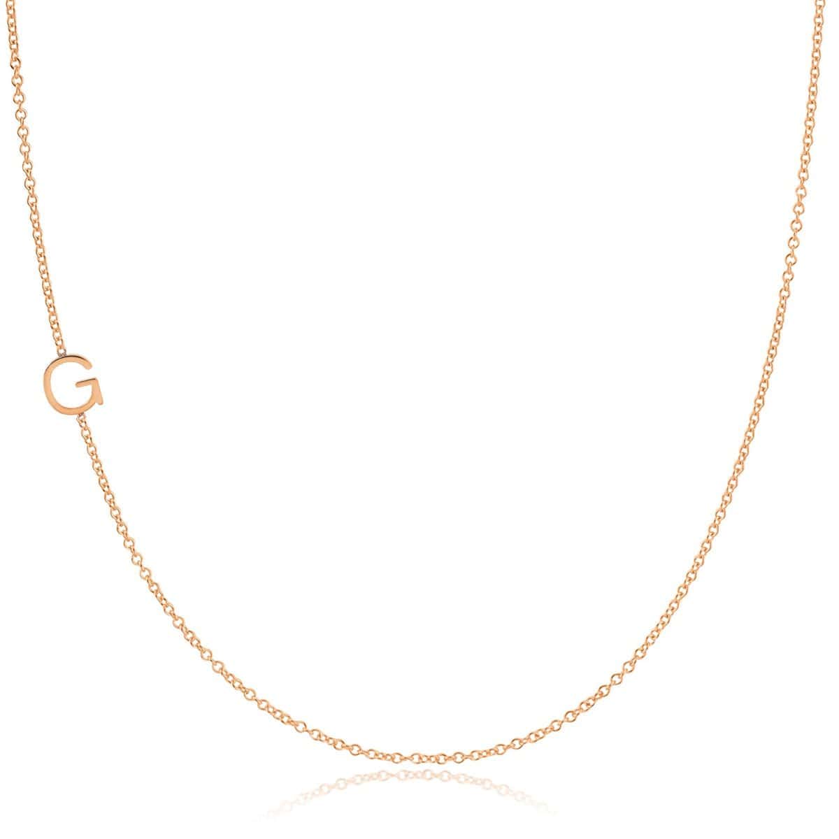 A rose gold necklace with a G letter charm on a white background. 