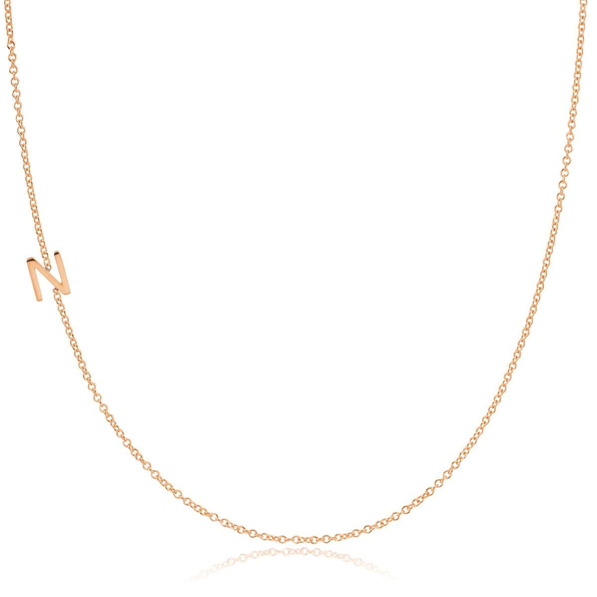 A rose gold necklace with an N letter charm on a white background. 