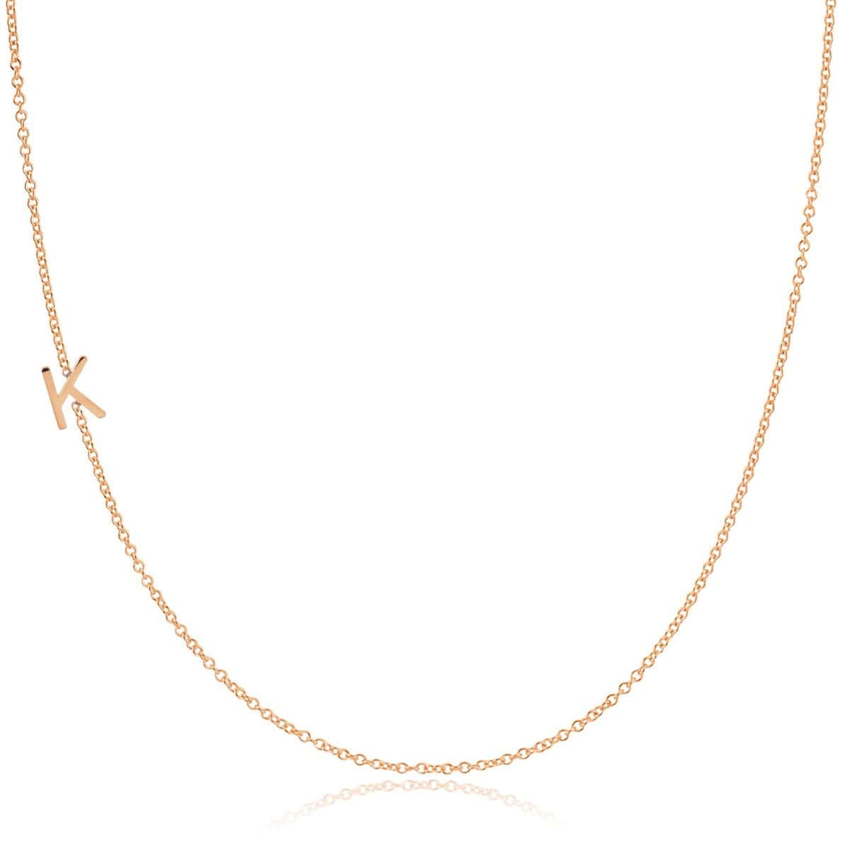 A rose gold necklace with a K letter charm on a white background. 