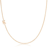 A rose gold necklace with a K letter charm on a white background. 