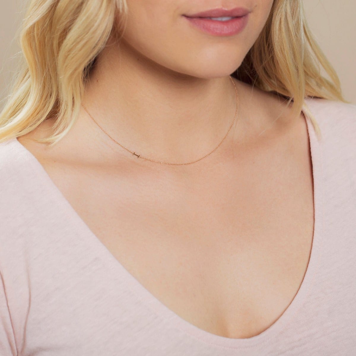 Close-up of a woman's neck wearing a white gold necklace with a letter I charm. 
