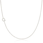 A white gold necklace with a G letter pave charm on a white background. 