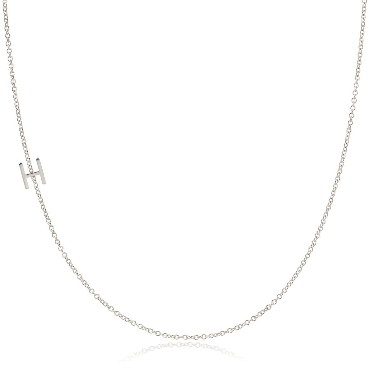 A white gold necklace with a H letter charm on a white background. 