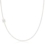 A white gold necklace with a H letter charm on a white background. 