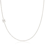 A white gold necklace with a H letter pave charm on a white background. 