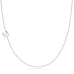 A white gold necklace with an M letter charm on a white background. 