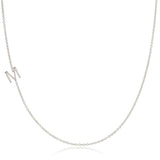 A white gold necklace with an M letter charm on a white background. 