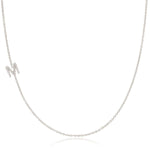 A white gold necklace with a letter M pave charm on a white background.