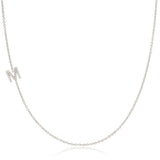 A white gold necklace with a letter M pave charm on a white background.