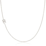 A white gold necklace with a letter R pave charm on a white background.