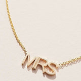 Close-up of a MRS Necklace in yellow gold on a cable chain on an off-white background. 