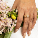 A hand wearing two The Daisy Bouquet Rings and holding a bunch of flowers. 