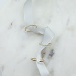 A Pave Diamond Ring, 4 Diamond Ring and Open Diamond Ring on white ribbon against a white marble background. 