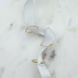 A Pave Diamond Ring, 4 Diamond Ring and Open Diamond Ring on white ribbon against a white marble background. 